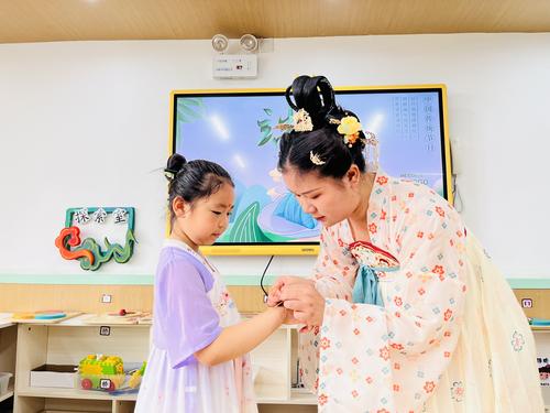 教师给幼儿佩戴五彩绳