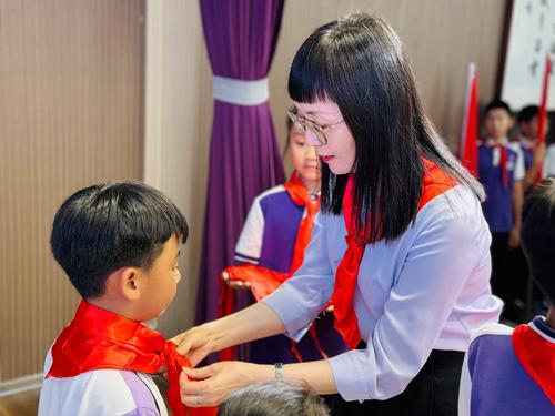 郑东新区龙翼小学党支部书记吕君莉为少先队员戴红领巾